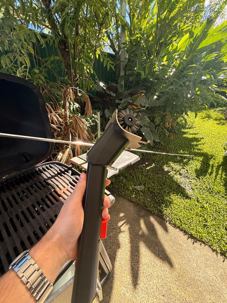 Customer holding the GRIZZLA Brush beside the BBQ